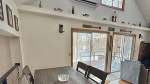 A dining area with a wooden table and chairs, a glass bowl, and a view of the outdoors through a glass door. - WATERFRONT ON SAND POND WITH A PRIVATE SANDY BEACH (East Baldwin)