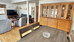 A spacious living area with a dining table, sofas, and a wooden cabinet. - WATERFRONT ON SAND POND WITH A PRIVATE SANDY BEACH (East Baldwin)