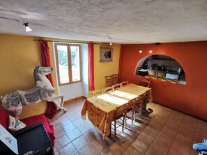 A dining area with a wooden table and chairs, a horse sculpture, and a kitchen visible through an archway. - Luminous gîte surrounded by animals on an organic farm in the Verdon region (Bargème)