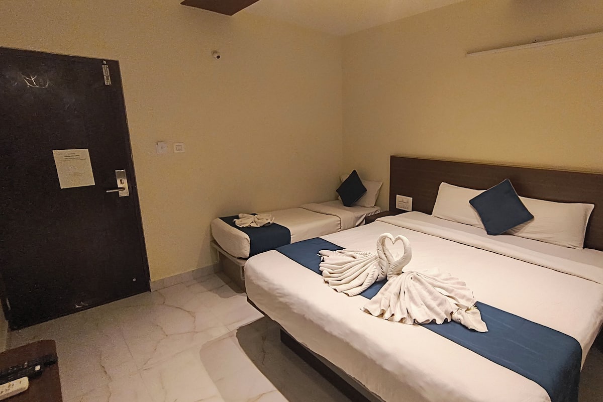Een hotelkamer met een groot bed, een kleiner bed en een bureau.