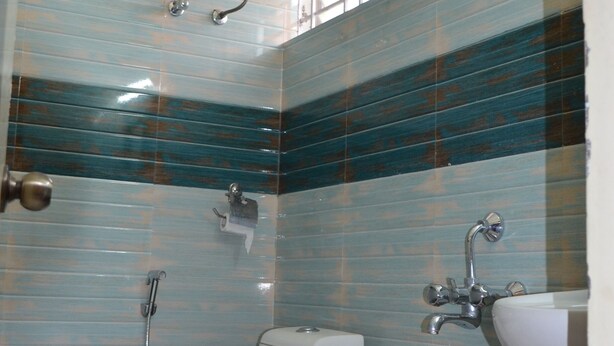 A bathroom with a toilet, a sink, a shower, and a water heater. - SKY LOFT HOTEL BANGALORE  INTL AIRPORT (Bengaluru)
