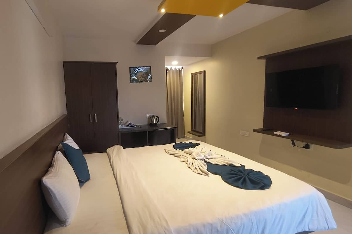 Een hotelkamer met een bed, een bureau, een televisie en een kledingkast.