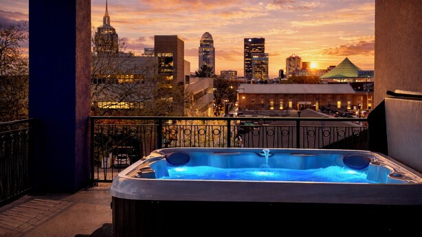 Un bain à remous sur un balcon offrant une vue sur la ville au coucher du soleil.