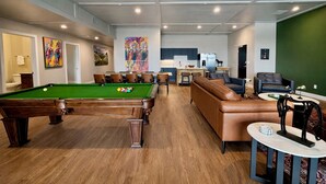 Une table de billard, un canapé, un coin repas et une cuisine dans un intérieur moderne.