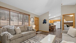 A spacious living room with a sofa, ottoman, and a dining area with a table and chairs.