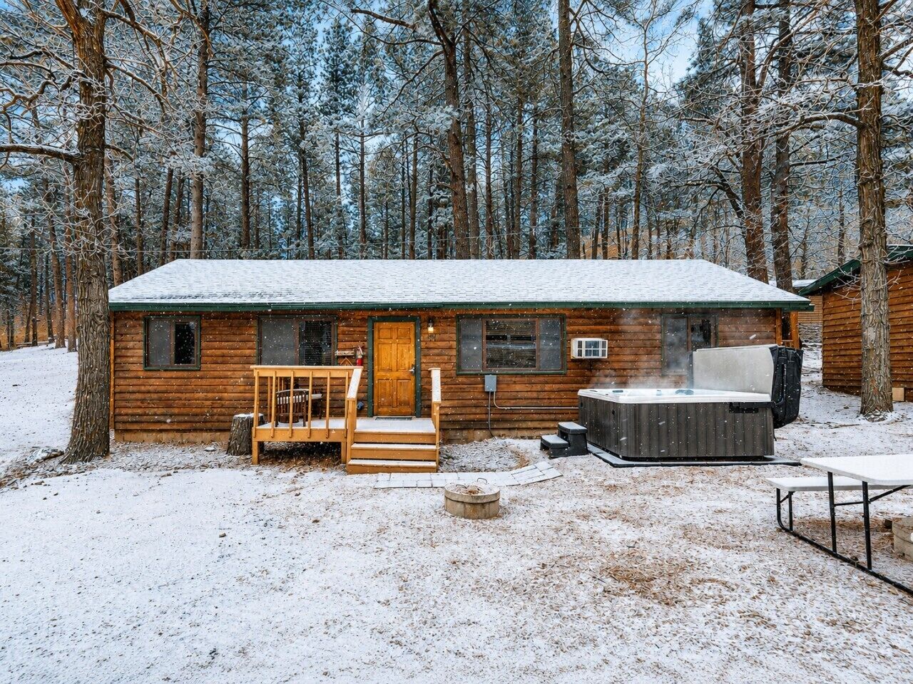Eine Holzhütte mit Whirlpool, einer Terrasse und einem überdachten Sitzbereich im Freien.