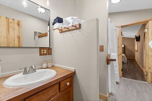 A bathroom with a wooden vanity, a large mirror, and a towel rack.