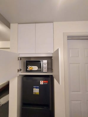 A compact kitchen with a microwave and a refrigerator, both with energy labels.