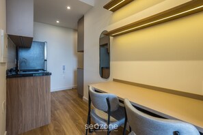 Une cuisine moderne équipée d’une cuisinière intégrée, d’un évier et d’un plan de travail en bois. On y trouve également un coin repas avec une table et deux chaises.