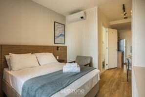 A hotel room with a bed, a chair, a desk, and an air conditioning unit. - Studio in Condo w/ Gym in Consolacao Mac0046 (São Paulo)
