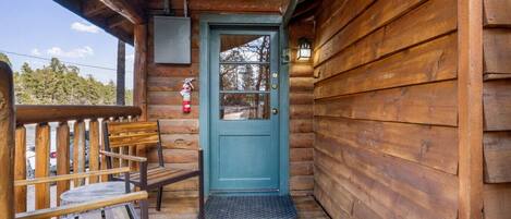 Une cabane en bois avec une porte bleue, un banc en bois et un extincteur fixé au mur.