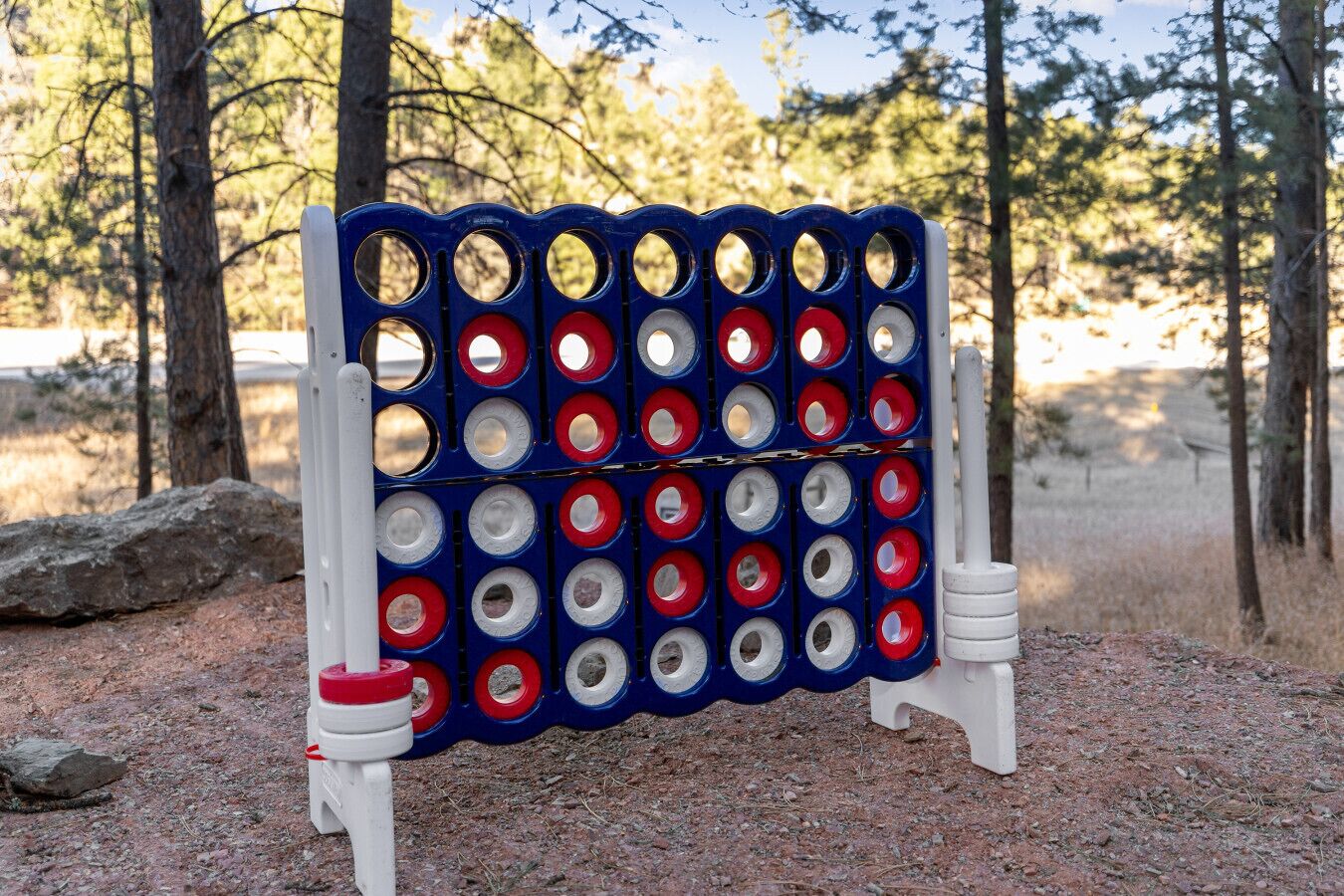 A game board with holes, set on a stand in a natural outdoor setting.