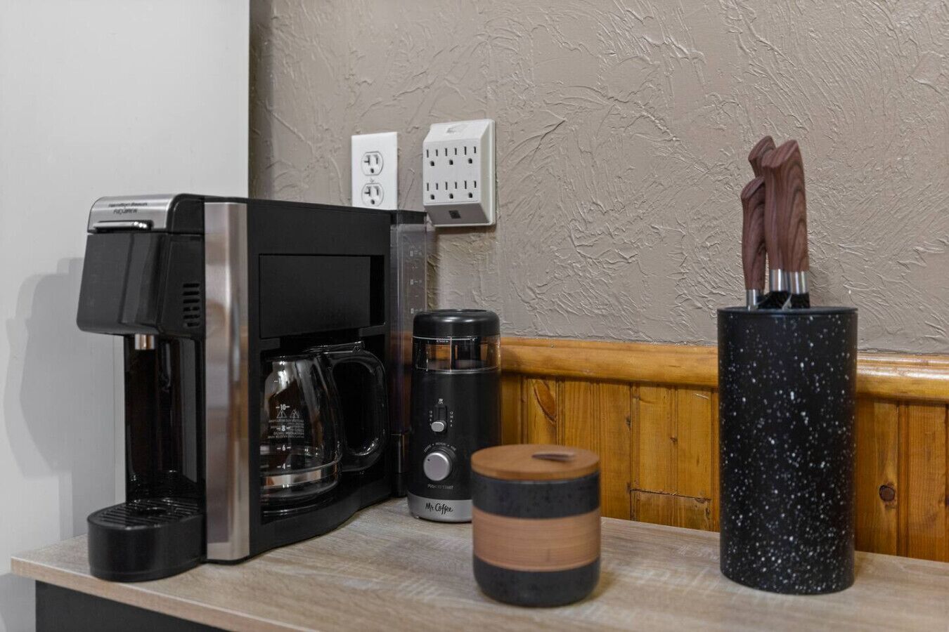 A coffee maker, a coffee pot, and a mug on a countertop.