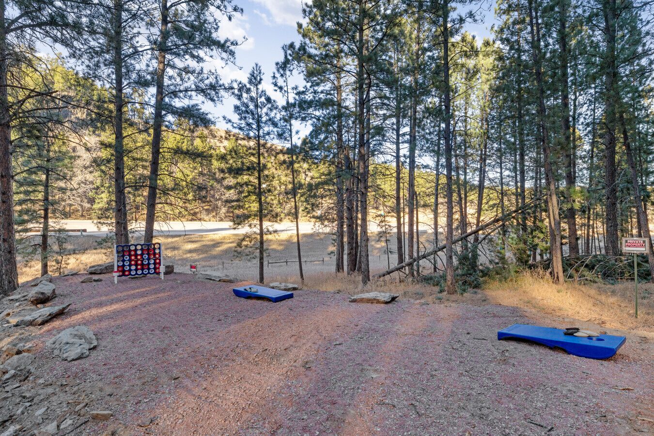 Skovområde med grussti, blå bænk og skilt med rød og hvid skrift, der angiver privat ejendom.