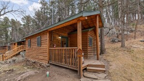 A log cabin with a porch and a staircase leading to a second level. - Angler’s Haven Cabin: Black Hills Quiet Escape (Rapid City)