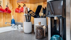 Eine Küche mit Kaffeemaschine, Gewürzbehälter und Kochutensilien auf der Arbeitsfläche.