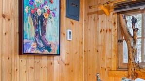 Ein Zimmer in einer Holzhütte mit einem Blumenbild, einer Lampe und einem gemütlichen Bett.