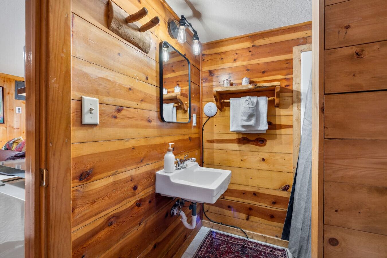 A wooden-paneled bathroom with a white sink, a mirror, and a towel hanging on a rack.