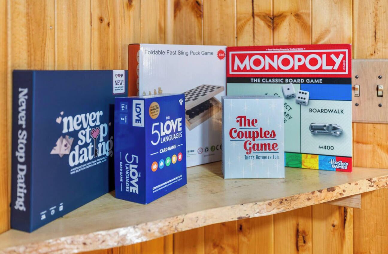 A shelf with various board games including Monopoly, Never Stop Dating, 5 Languages, and The Couples Game.