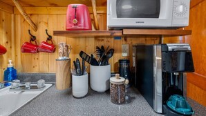 Eine kleine Küche mit Mikrowelle, Kaffeemaschine und verschiedenen Küchenutensilien.