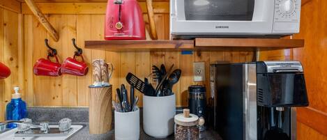 A compact kitchen with a microwave, coffee machine, and various utensils.