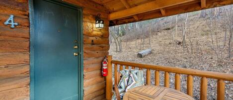 Une cabane en bois avec une porte verte, un extincteur et une petite table sur le porche.