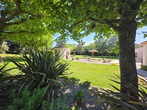 A well-maintained garden with a patio area, a small gazebo, and a variety of plants.
