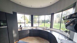 A modern kitchen with a curved layout, large windows, and a view of the outdoors. - Charming Provencal villa with pool Cabriès (Cabriès)