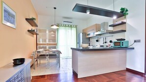 Una cucina moderna con isola centrale, mobili in legno e zona pranzo con tavolo in vetro.