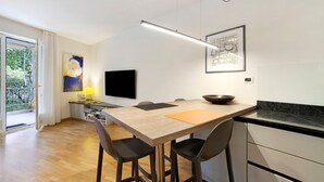 Une cuisine moderne avec une table en bois, des tabourets de bar, un téléviseur à écran plat et une grande fenêtre.
