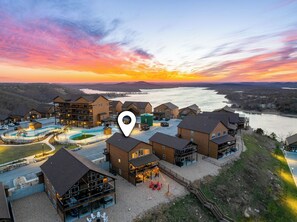 A resort with multiple buildings, a swimming pool, and a view of a lake at sunset. - 7 Ensuites, Hot Tub, Indoor Pool, Views, EV, Games (Kimberling City)