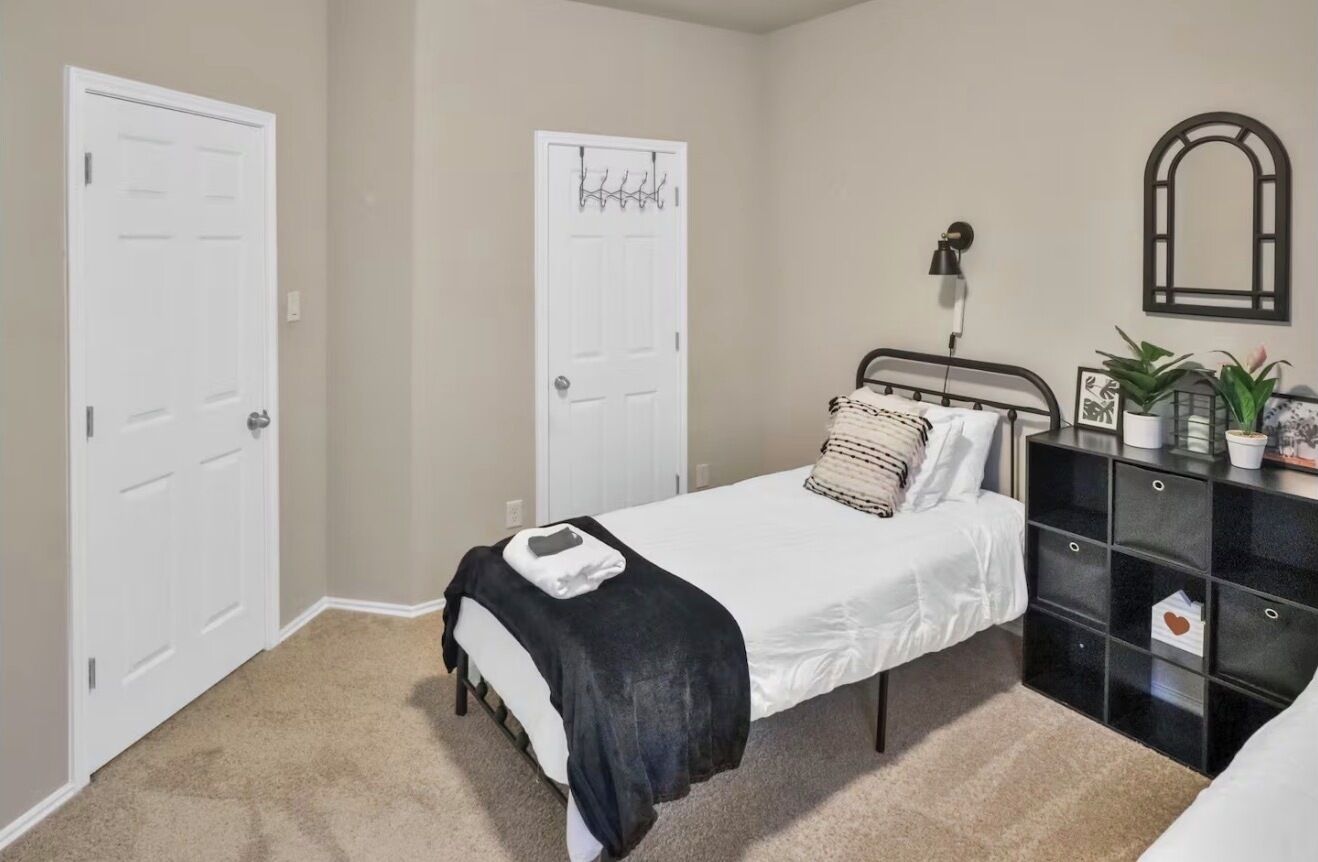 Une chambre à coucher avec un lit, une commode, un miroir et deux portes.