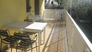 A balcony with a table and chairs, a washing machine, and a small table.