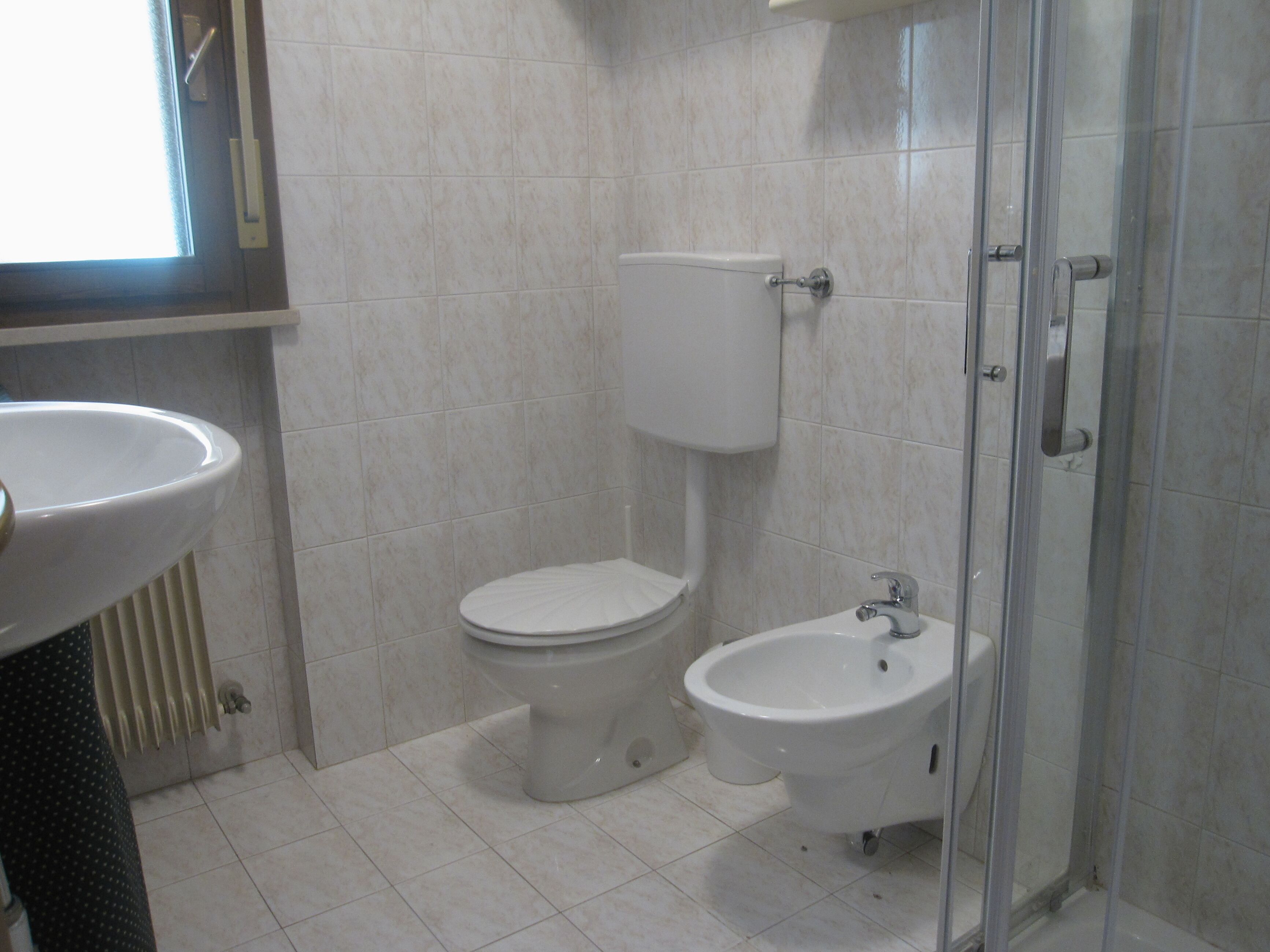 A bathroom with a toilet, bidet, and a sink.