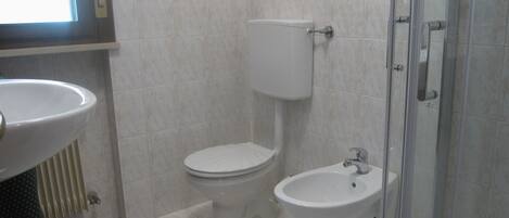 A bathroom with a toilet, bidet, and a sink.