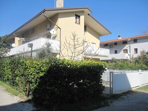 Une maison à deux étages avec un balcon, une antenne parabolique et une clôture blanche.