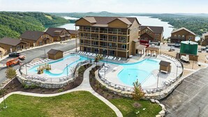 A hotel with a large pool area, multiple buildings, and a view of a lake. - Luxury Cabin Private Hot Tub and Steps to Pools! (Kimberling City)