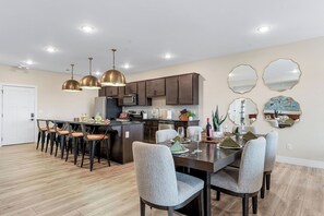 Une cuisine moderne avec des meubles de couleur sombre, un îlot central et des luminaires suspendus.
