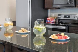 A kitchen counter with a pitcher of water, a plate of pastries, and a plate of fruit. - Luxury Condo Over Lazy River & Private Hot Tub (Kimberling City)