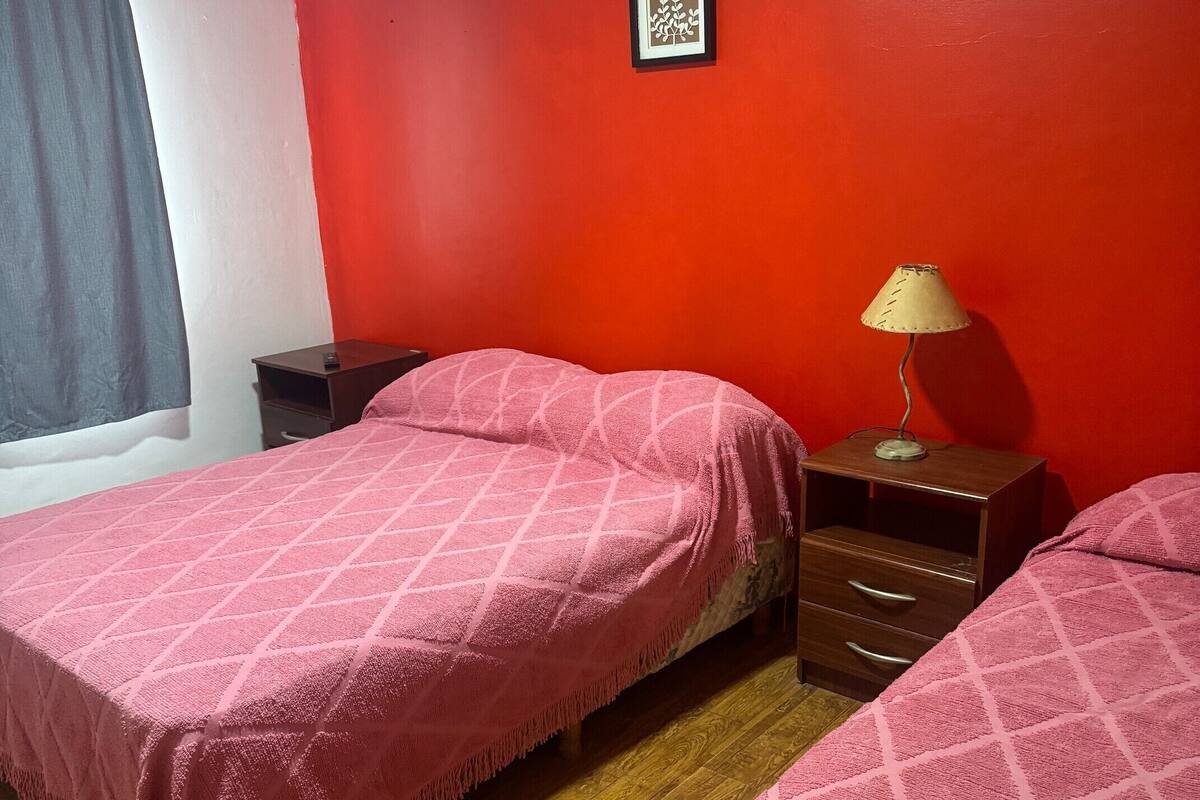Een kamer met twee bedden, een nachtkastje, een lamp en een aan de muur hangend schilderij.