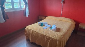 A single bed with a yellow quilt, two rolled towels, and a small bedside table with a lamp. - HOSTERIA  AILEN (Ushuaia)