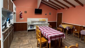 A dining area with wooden tables and chairs, a television mounted on the wall, and a water dispenser on the counter. - HOSTERIA  AILEN (Ushuaia)