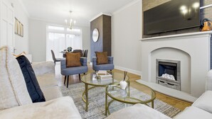 Una sala de estar moderna con chimenea, televisor de pantalla plana y asientos cómodos.