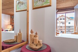 A wooden interior with a round table, a mirror, and framed artwork on the wall. - Ciasa monaco a gem in the heart of the dolomites (Corvara in Badia, Bolzano Alto Adige)