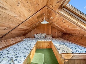 Een gezellig slaapkamer op zolder, met schuine wanden, een eenpersoonsbed en een dakraam.