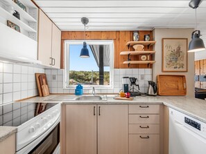 Een moderne keuken met een groot raam, houten kastjes en een inbouw vaatwasser.
