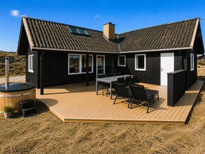 Una casa moderna con terraza, zona de barbacoa y sauna.