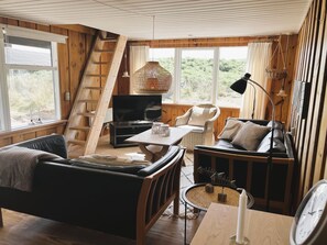 A cozy cabin interior with a sofa, a television, a dining table, and a wicker chair. - "Monna" -  from the sea by Interhome (Hvide Sande)