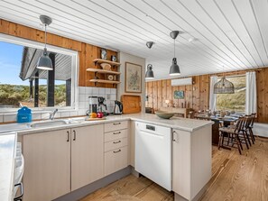 Une cuisine moderne agrémentée d’éléments en bois, dotée d’un lave-vaisselle et comprenant un coin repas avec vue.