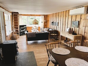 Un interior de cabaña acogedor con sala de estar, comedor y chimenea.